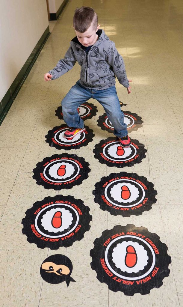 Elementary student walks on a sensory floor.